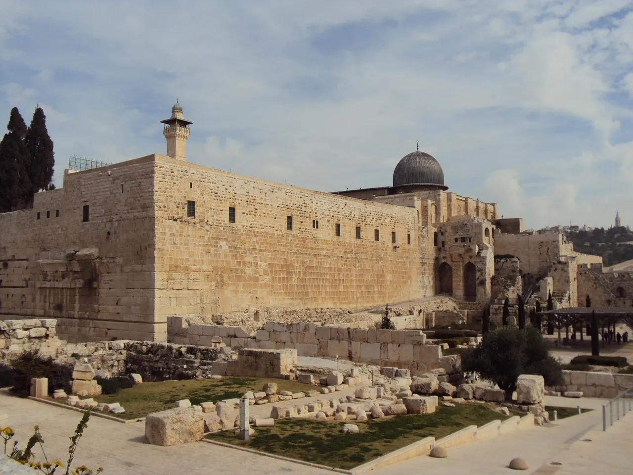 The southern wall of Jerusalem's Temple Mount with archaeological remains in the foreground and the Al-Aqsa Mosque dome visible behind the ancient stones