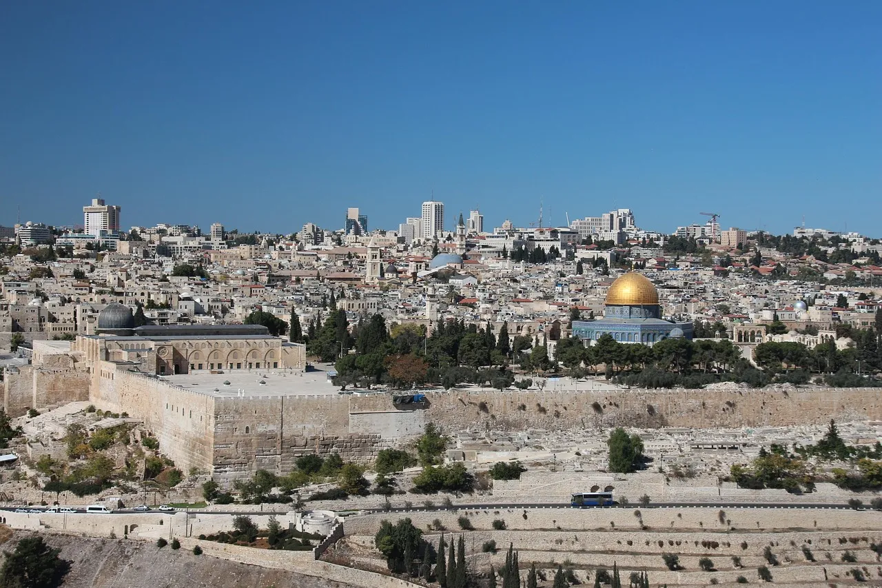 Jerusalem rooftop view looking across domed rooftops toward the Old City walls and Dome of the Rock at sunset