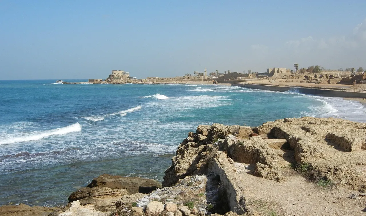 The ancient Roman aqueduct at Caesarea stretching along the Mediterranean beachfront, with arched columns standing against the sea
