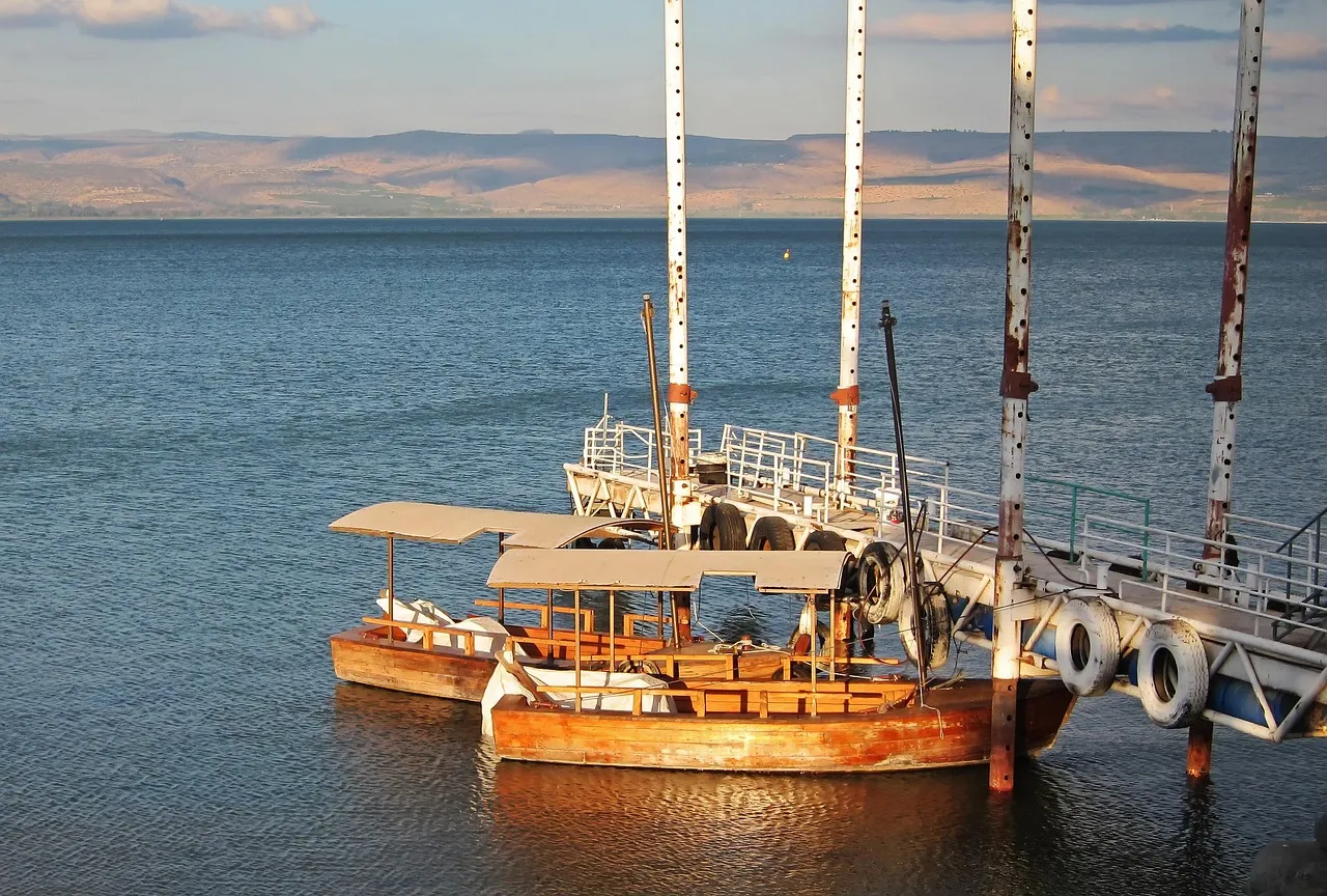 Traditional wooden boat on the Sea of Galilee with calm water and green hills in the background