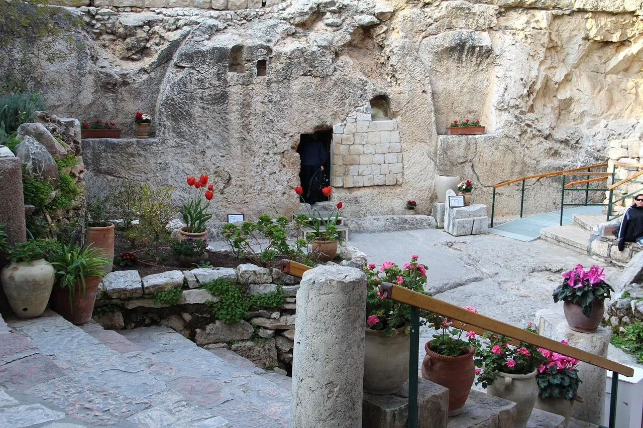 The rock-cut tomb and garden grounds of the Garden Tomb in Jerusalem, with flowering plants framing the entrance to the burial chamber